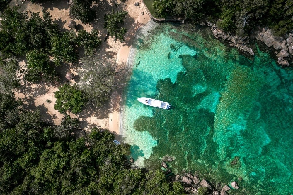 Aerial view of a boat in a turquoise cove on Jamaica’s north coast