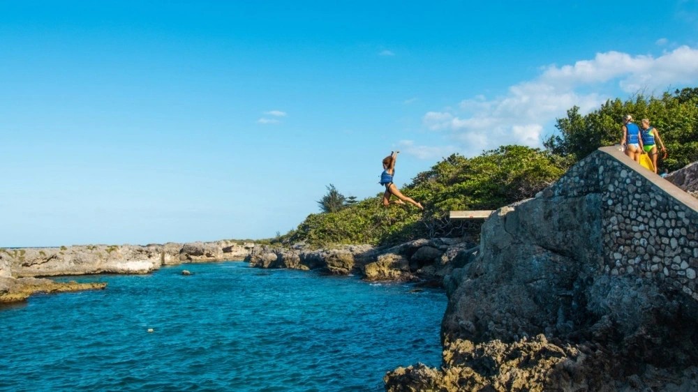 Visitors cliff jumping into clear water on Jamaica’s west and south coasts