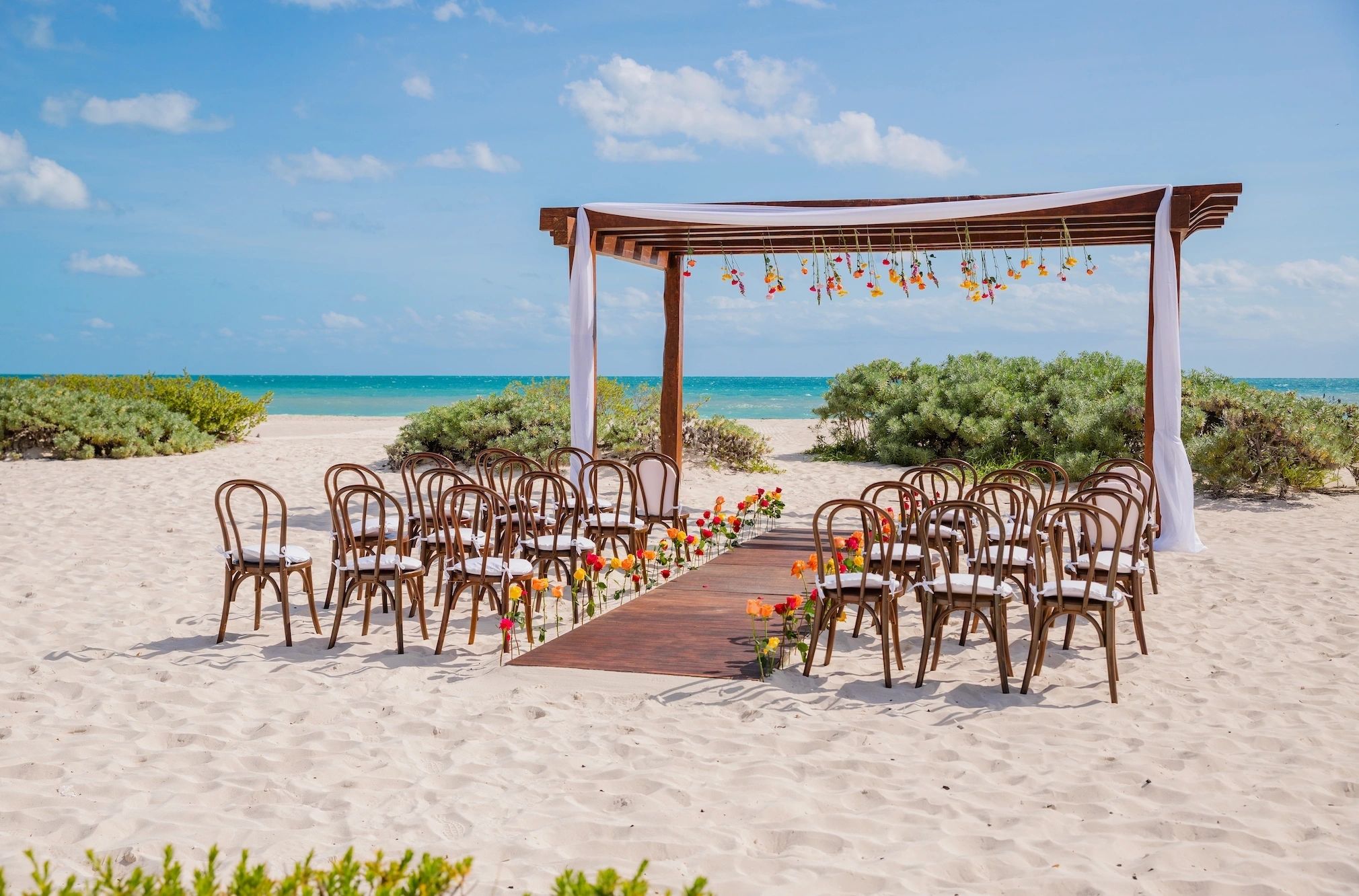 Rustic beach ceremony arch and wooden chairs