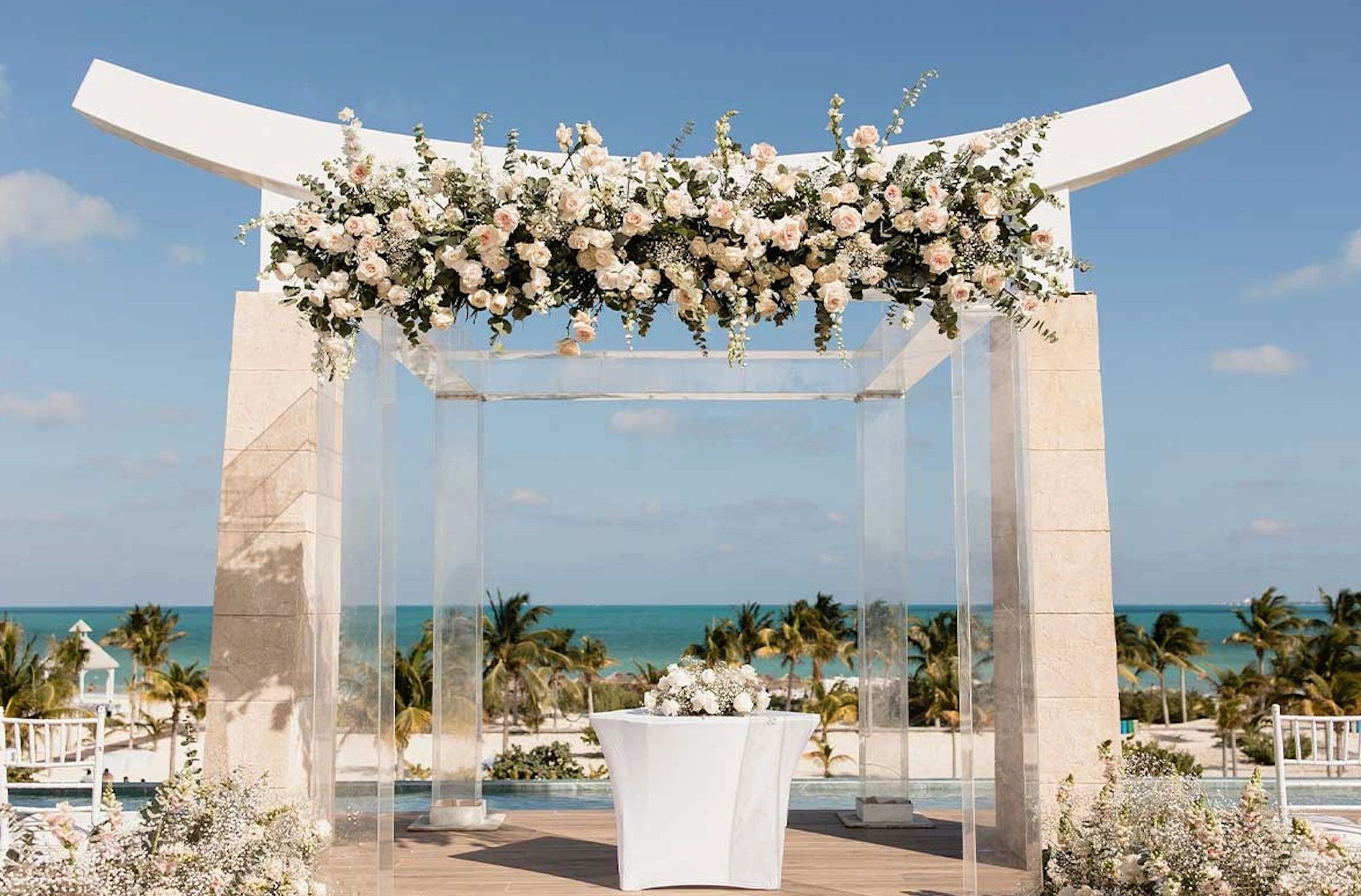 White beach wedding arch decorated with flowers